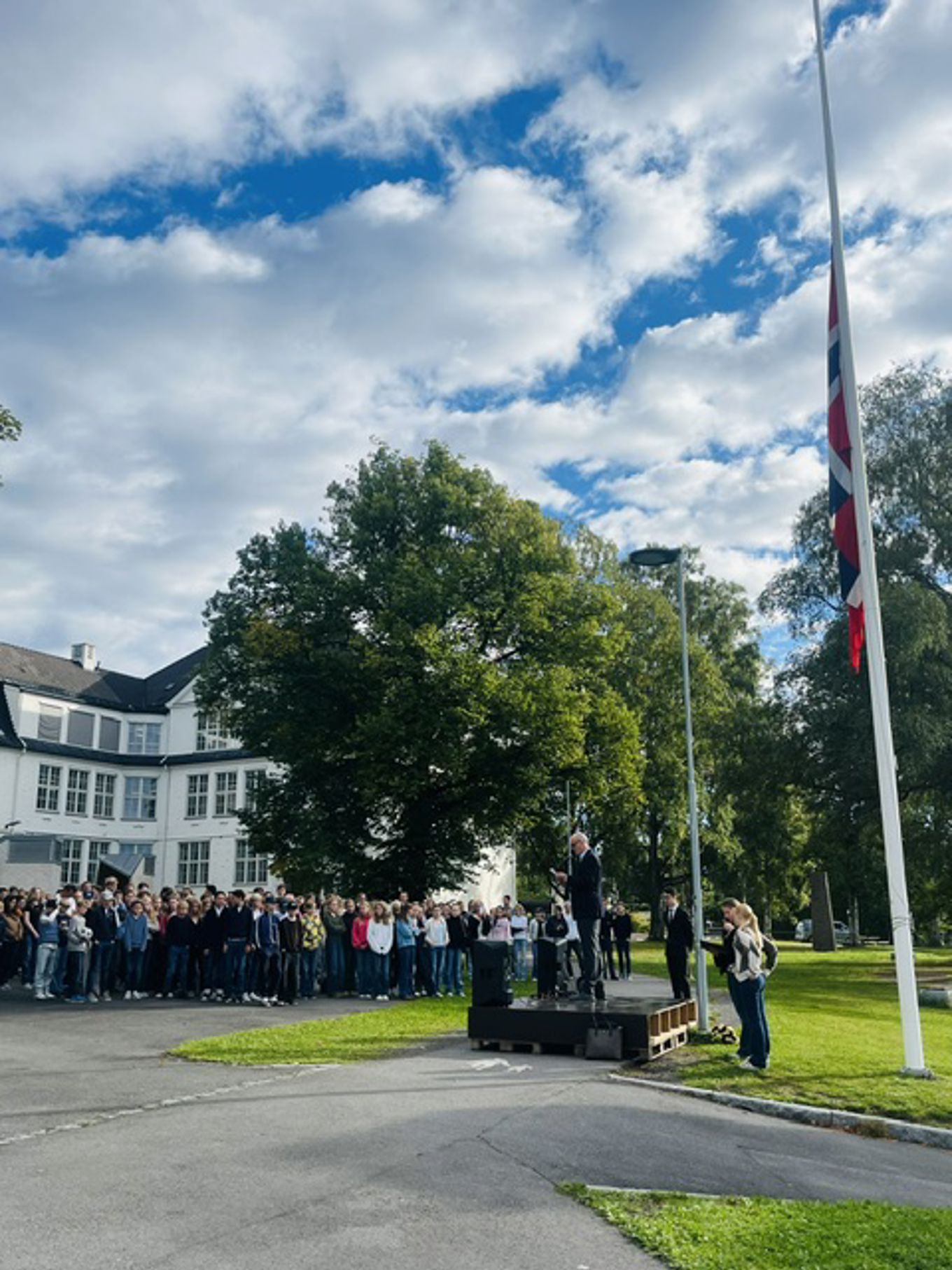 En gruppe mennesker som står på en gate med et flagg og et flagg
