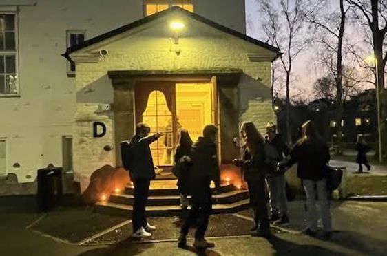 en gruppe mennesker som står utenfor et hus